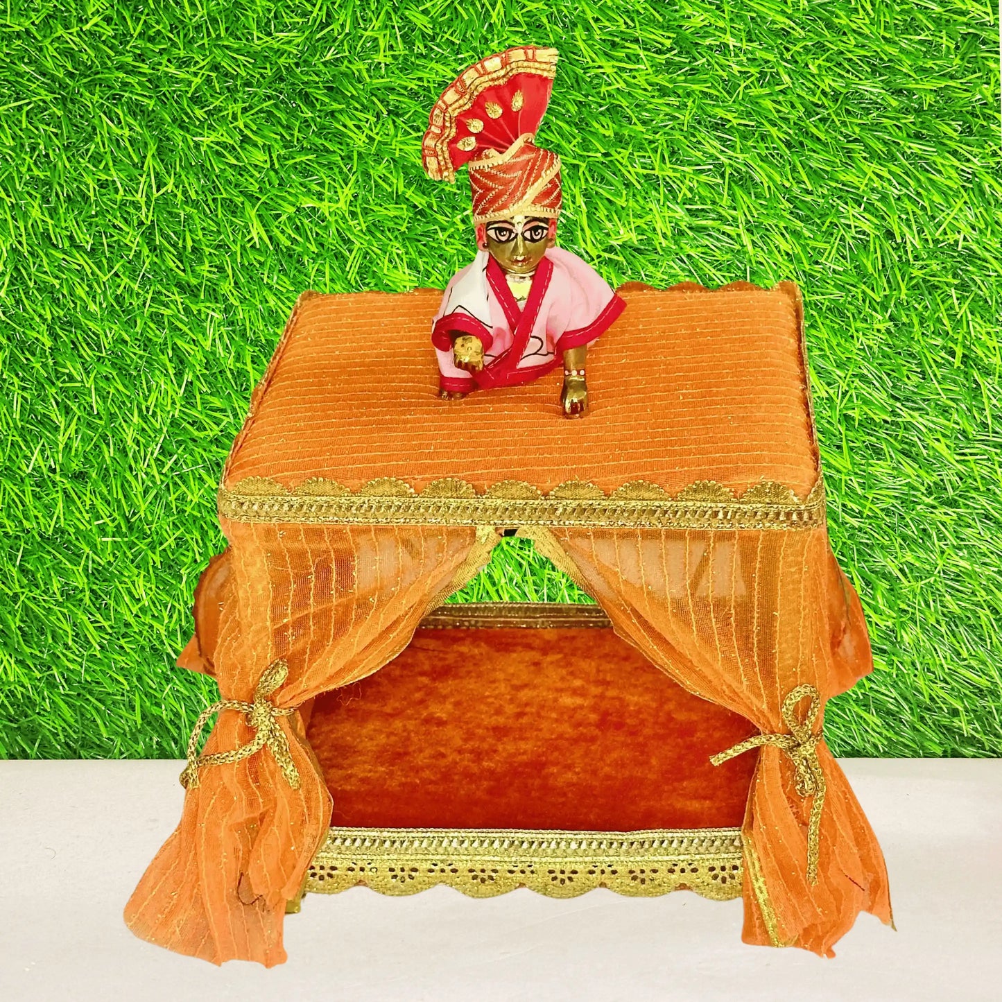 Kanha ji sitting on an Elegant Orange Decorative Laddu Gopal Singhasan with Designer Jhula with Curtains.