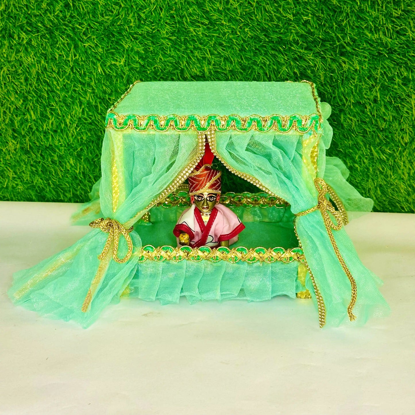 Front view of kanha ji sitting in a Elegant Sea Green Laddu Gopal Jhula Singhasan with Golden Lace Border.