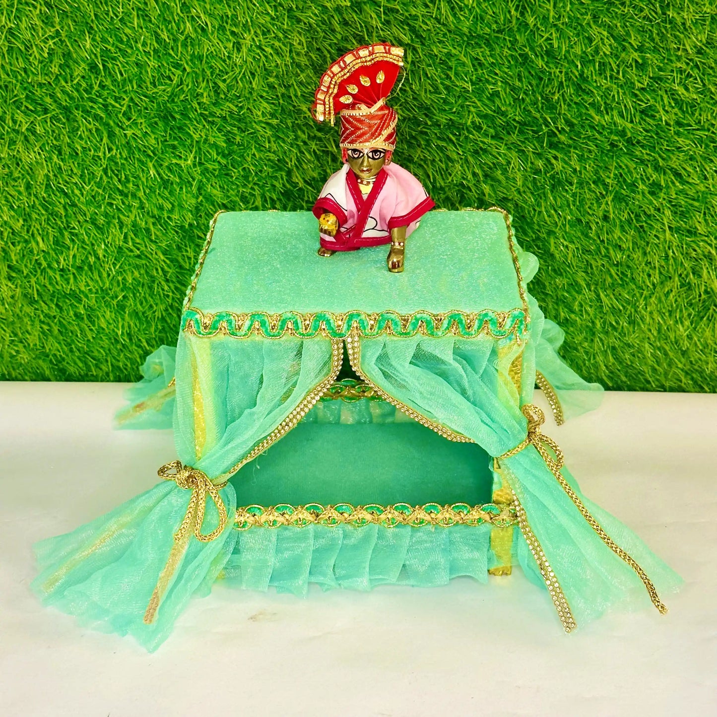 Front view of kanha ji sitting on a Elegant Sea Green Laddu Gopal Jhula Singhasan with Golden Lace Border.
