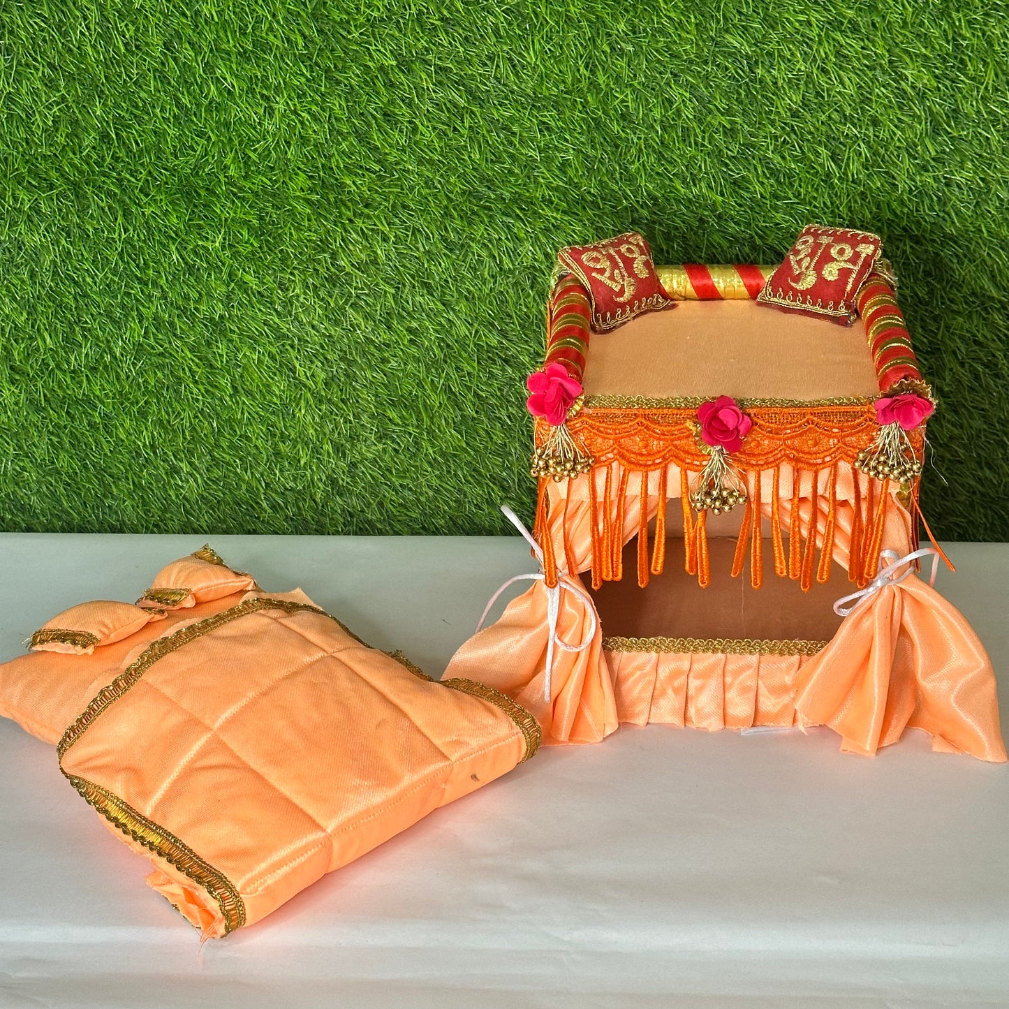 Peach color laddu gopal ji singhasan with complete bedding set including mattress, pillows, and blanket.