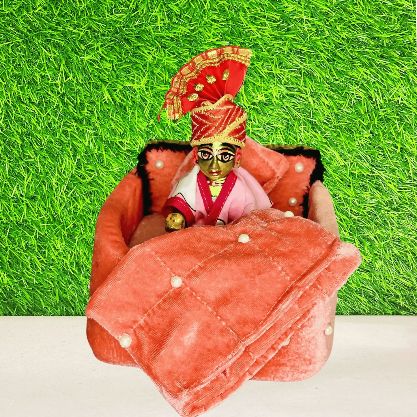 Laddu gopal sitting in a Premium Peach Shaneel Laddu Gopal Bedding Set with Pearl Work Blanket & Pillow.