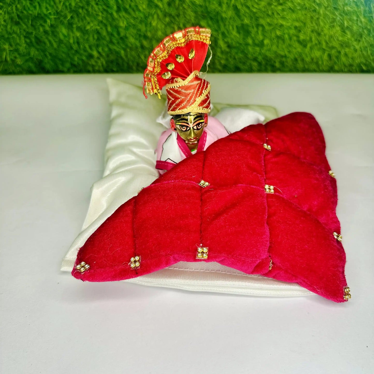 Laddu Gopal ji sitting in a Royal Red Velvet Laddu Gopal Bedding Set with Golden Stone Work Blanket & Satin Base