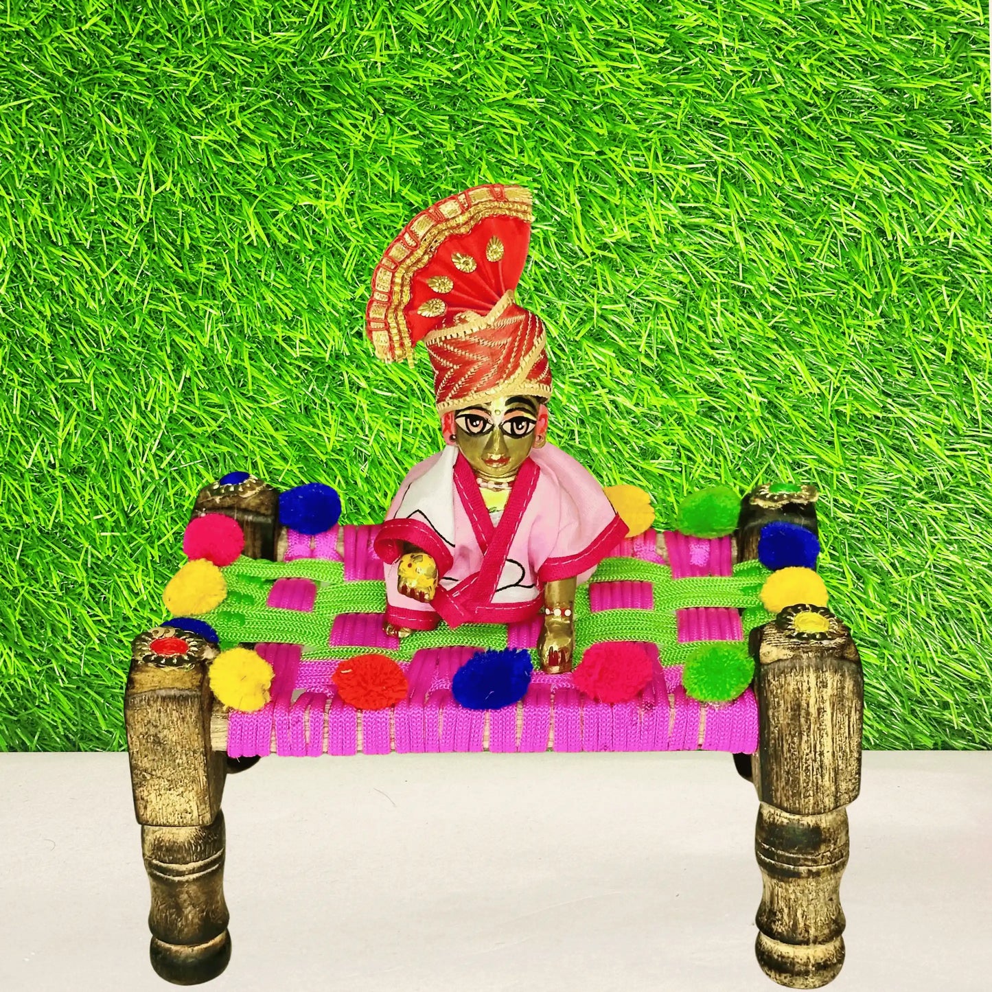 Kanha ji sitting on a Traditional Multicolor Pom-Pom Charpai for Laddu Gopal Ji.