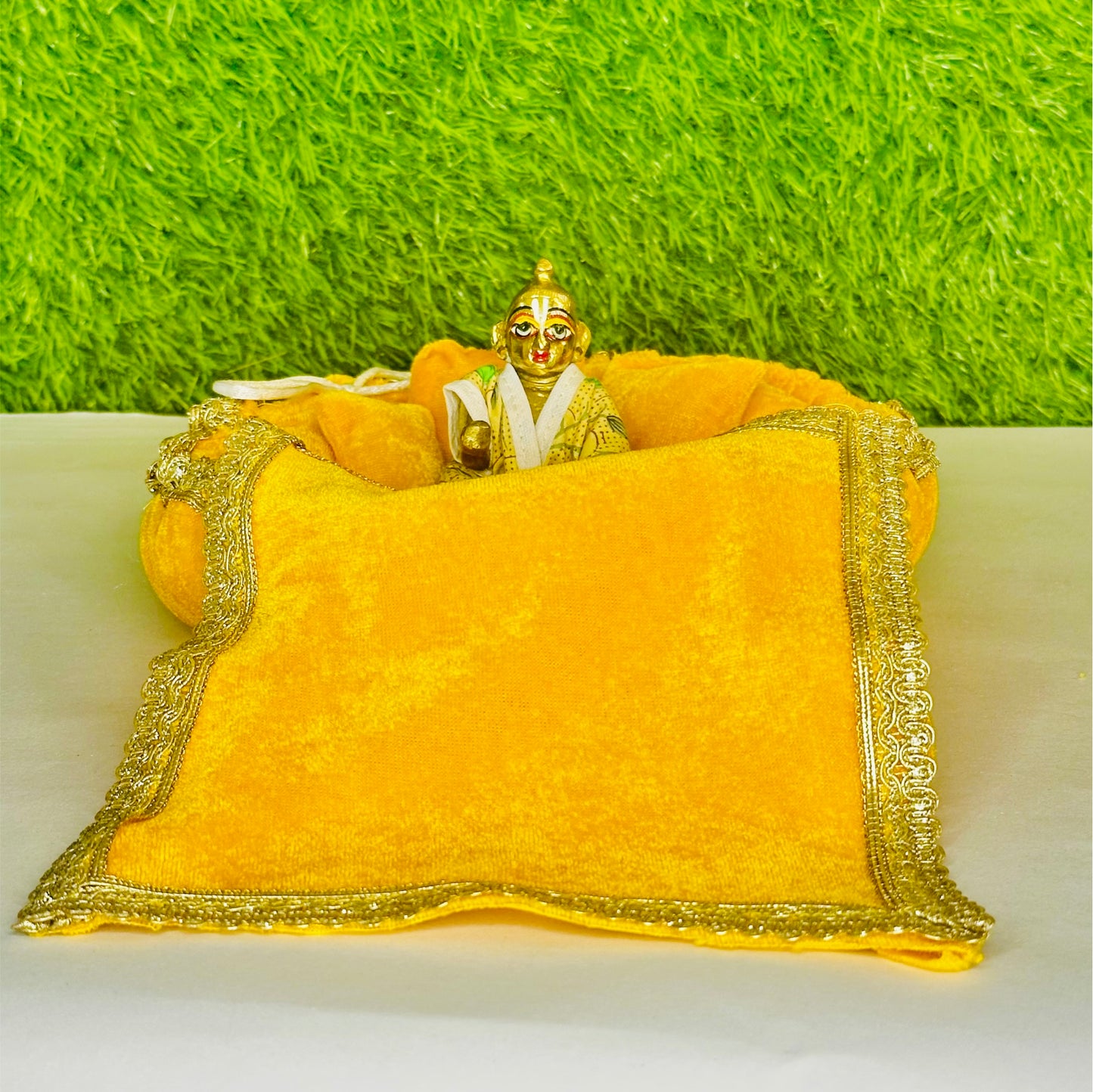 Front view of Kanha ji sitting on a Yellow Shaneel Laddu Gopal Bedding Set with Blanket & Pillow.