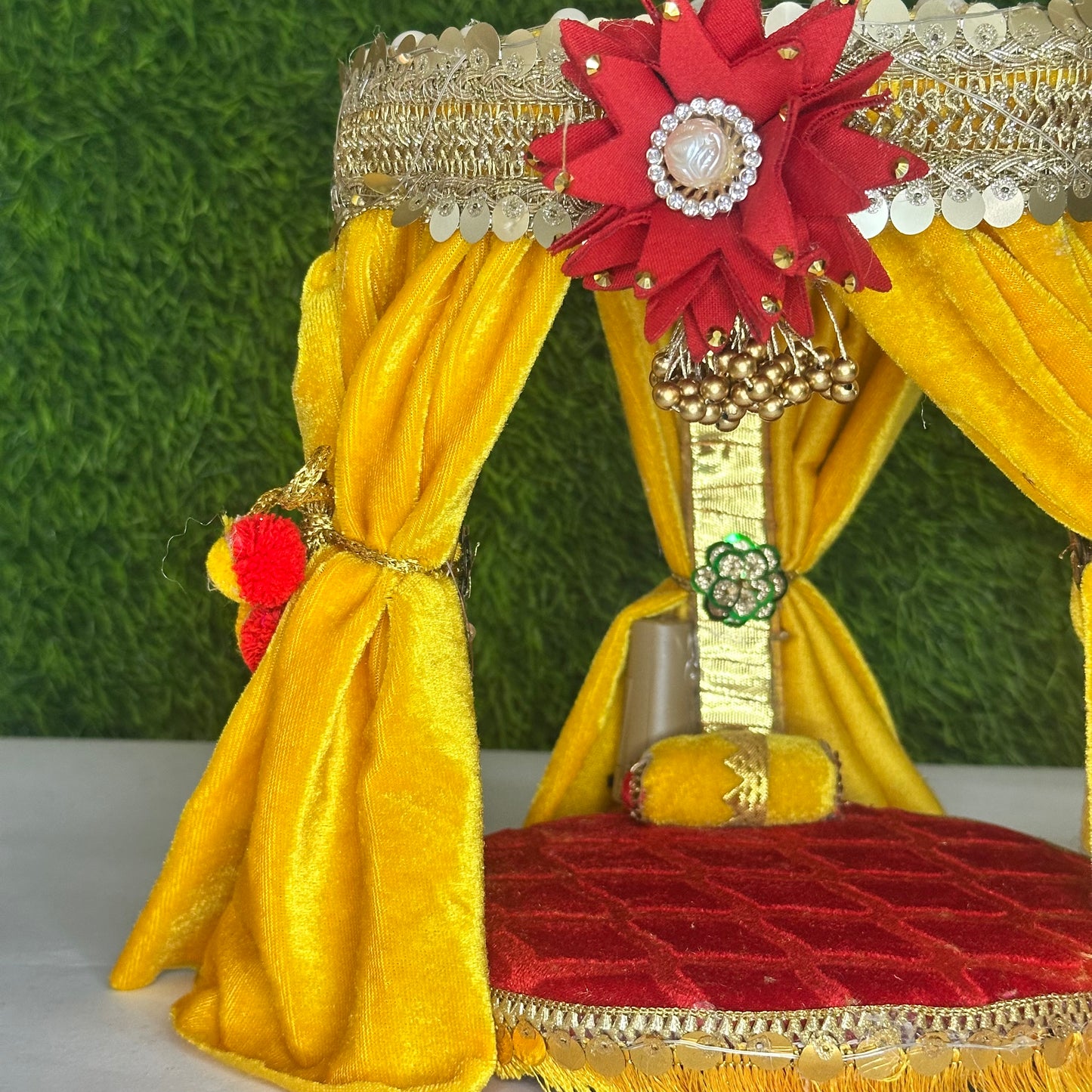 Left close up view of a Royal Yellow Velvet Singhasan for kanha Ji with Pom-Pom Curtains, Pearl Decoration & LED Lights.